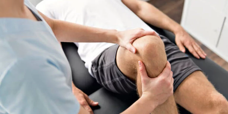 image of a man getting his knee treated by a physical therapist
