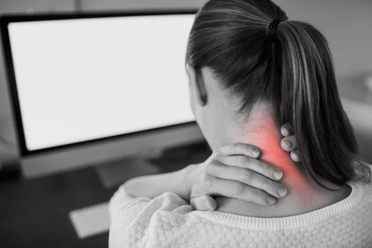 image of a woman at a computer terminal suffering from neck pain