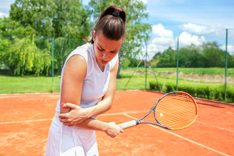 image of a woman playing tennis suffering from elbow pain