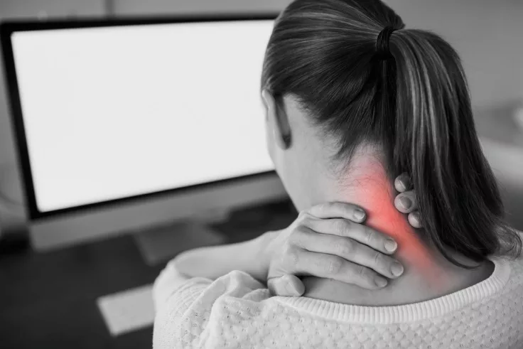 woman with neck pain sitting in front of a computer